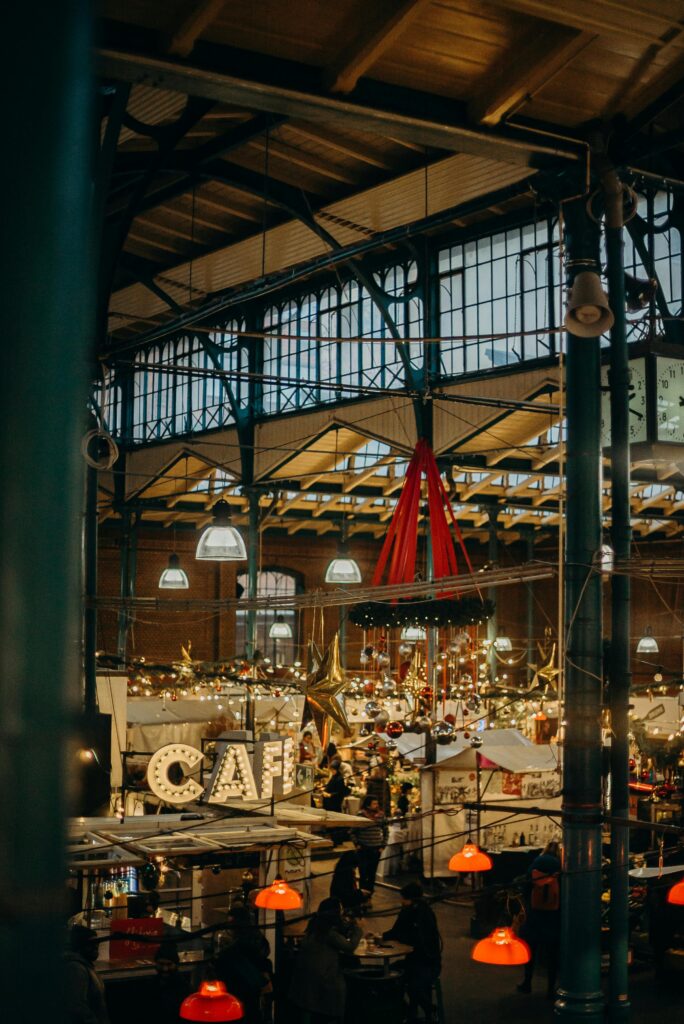 Warm and festive atmosphere of an indoor Christmas market with a cozy café setting.